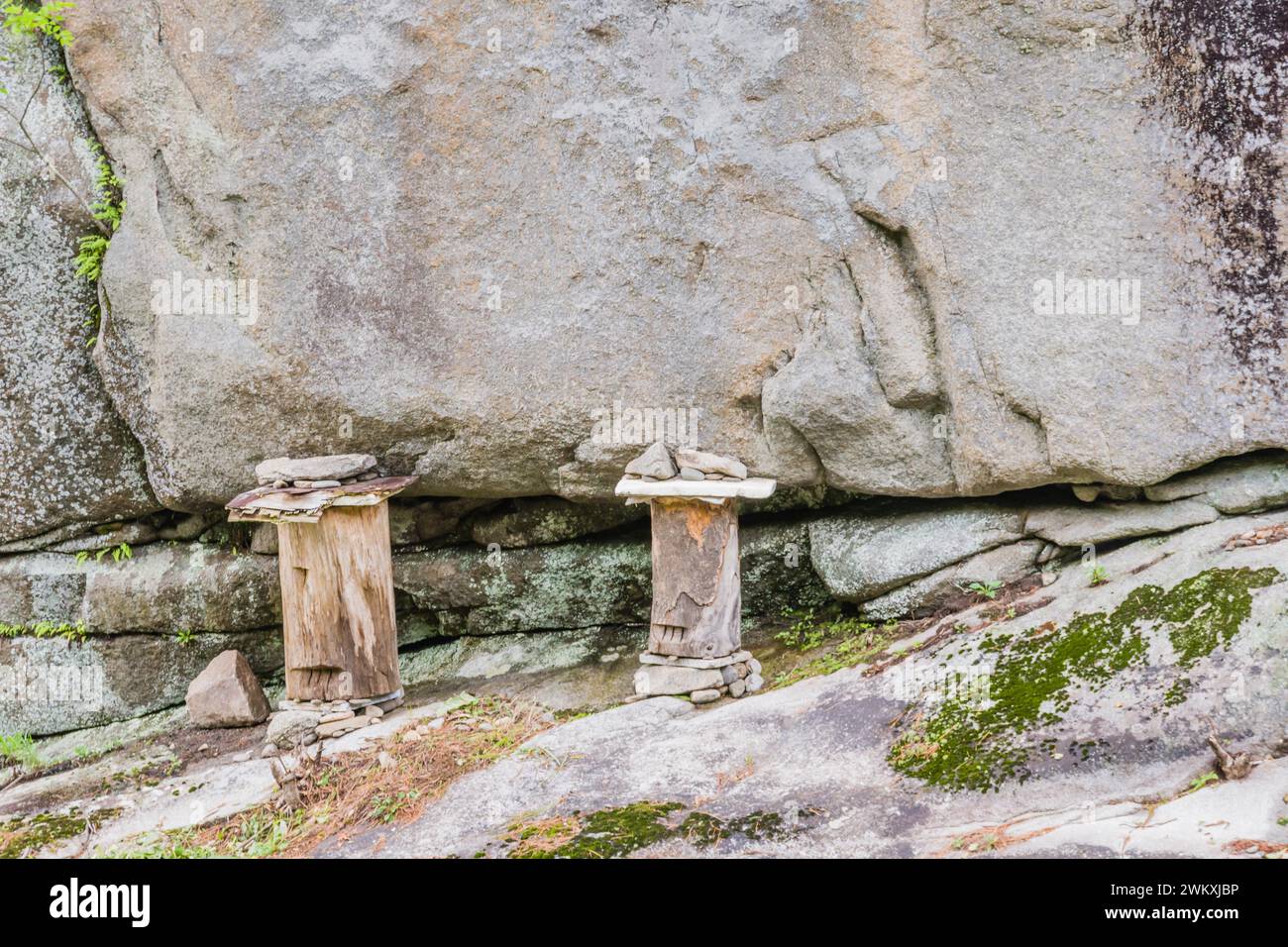 Deux bûches maintenues en place avec des pierres et sculptées pour avoir un œil et une bouche sur le rebord rocheux de la falaise dans la campagne en Corée du Sud Banque D'Images
