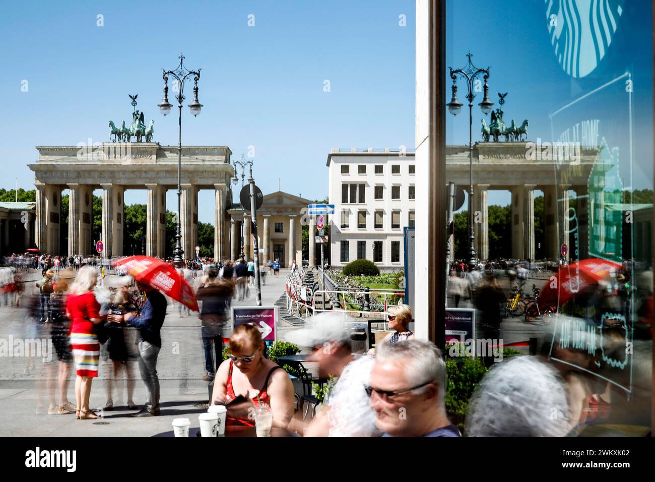 La porte de Brandebourg se reflète dans une vitre. Une longue exposition montre les touristes au Cafe am Brandenburg Gate, Berlin, 06.05.2018 Banque D'Images