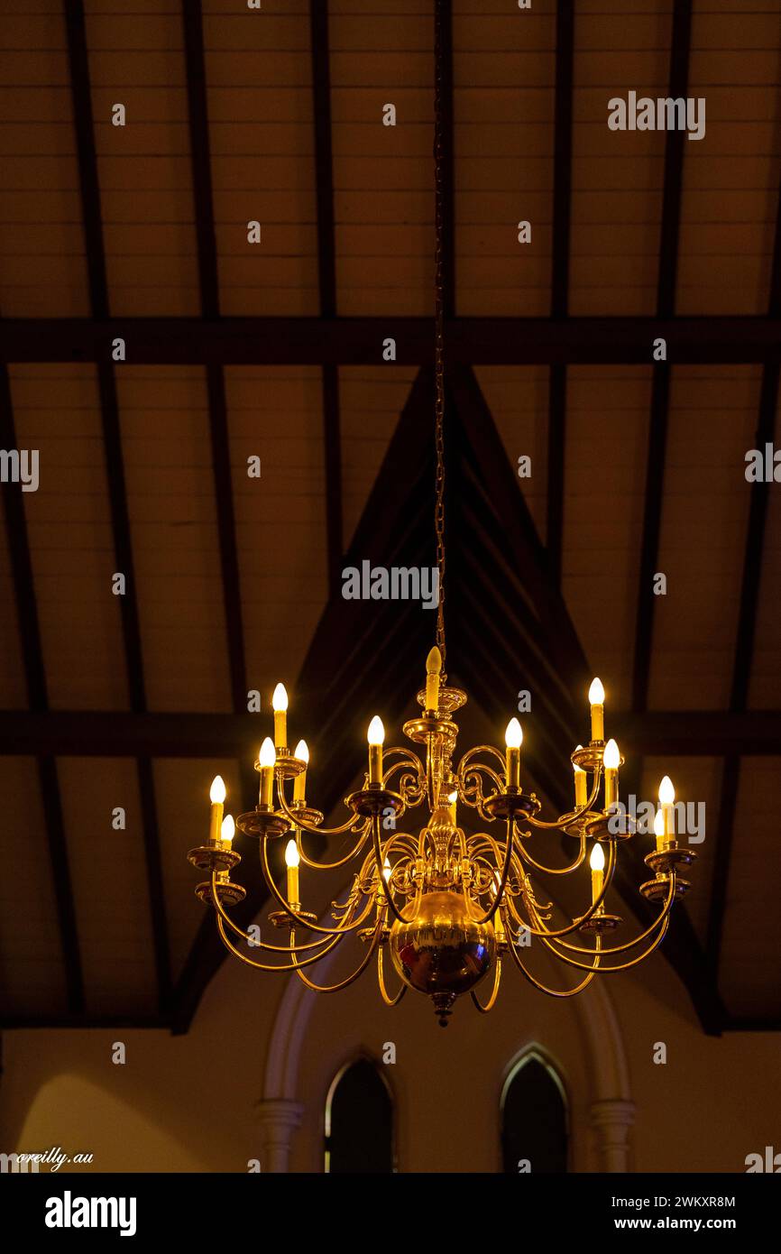 Vue nocturne de l'intérieur d'une église vintage avec un lustre lumineux et des vitraux Banque D'Images