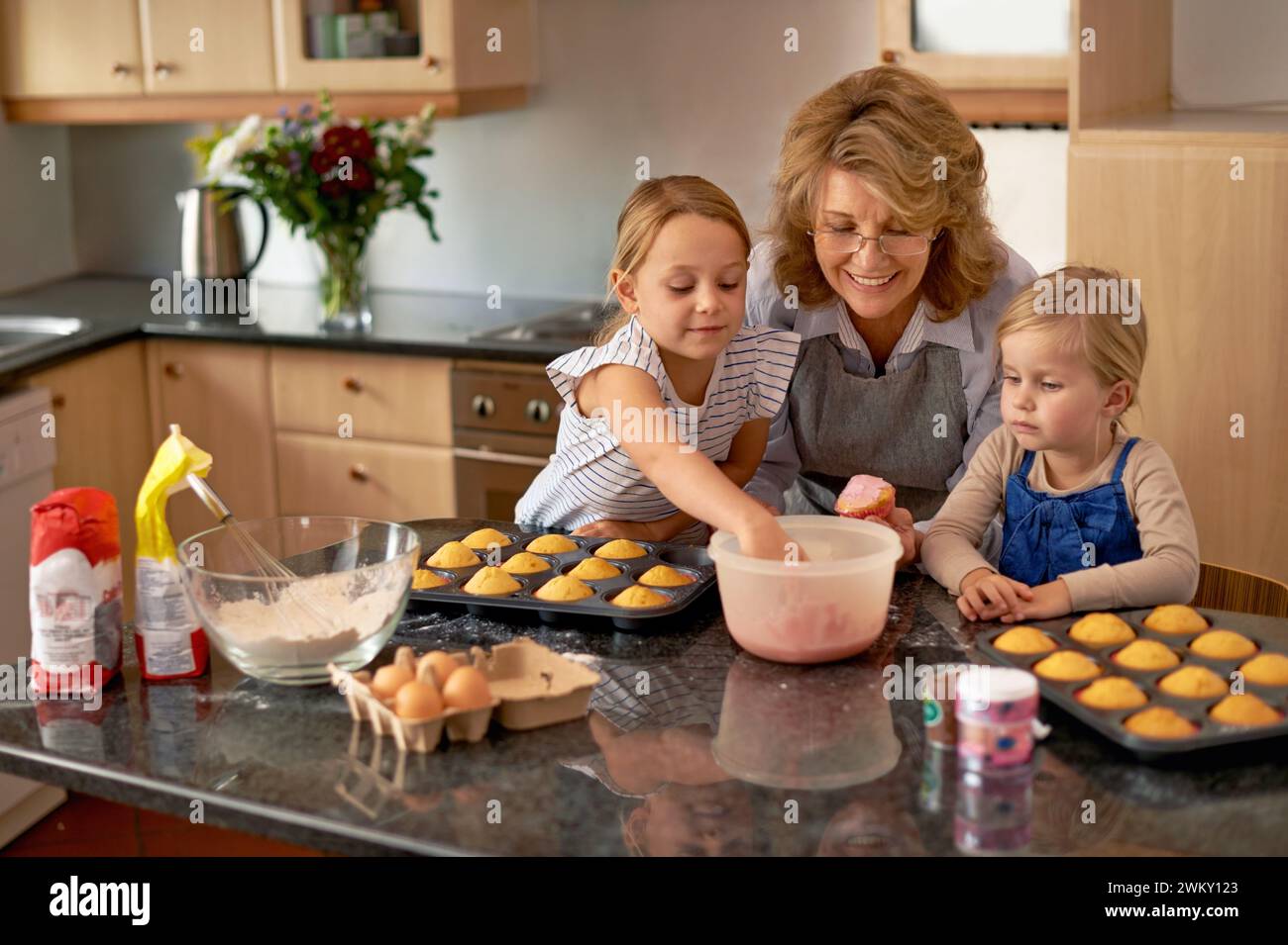 Grand-mère, enfants et faire des cupcakes ou aider avec des décorations de glaçage ou apprendre la créativité, la création de liens ou le travail d'équipe. Femme, frères et sœurs et doux Banque D'Images