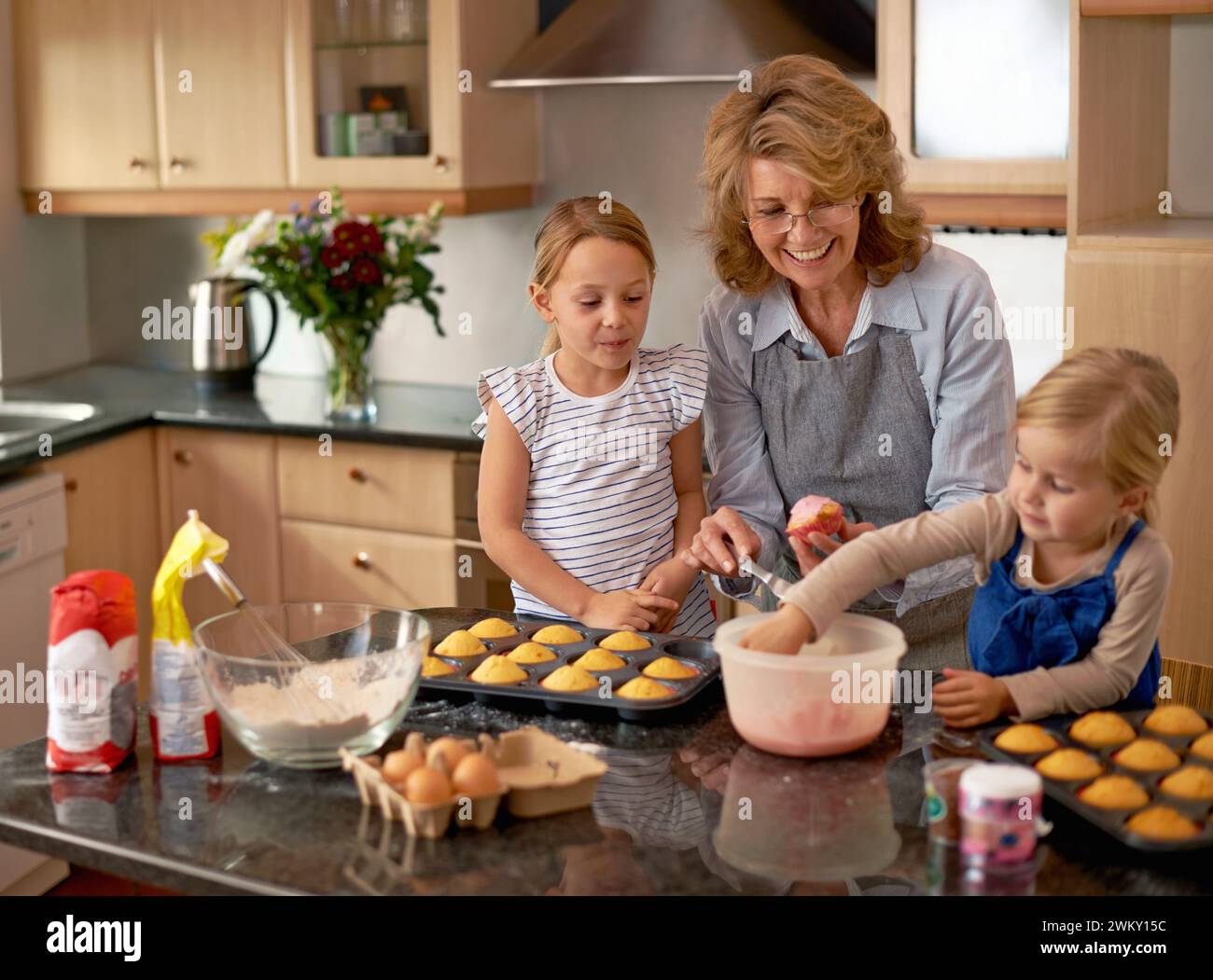 Grand-mère, enfants et faire des cupcakes ou enseigner avec des décorations glaçantes ou apprendre la créativité, la liaison ou le travail d'équipe. Femme, frères et sœurs et doux Banque D'Images