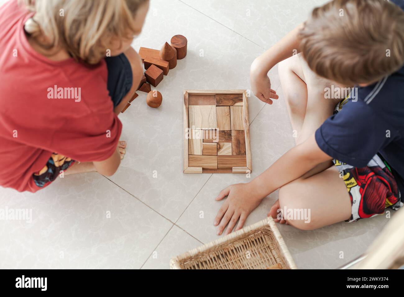 Un tweens jouant des jouets de blocs de construction en bois ensemble dans un intérieur minimaliste léger Banque D'Images