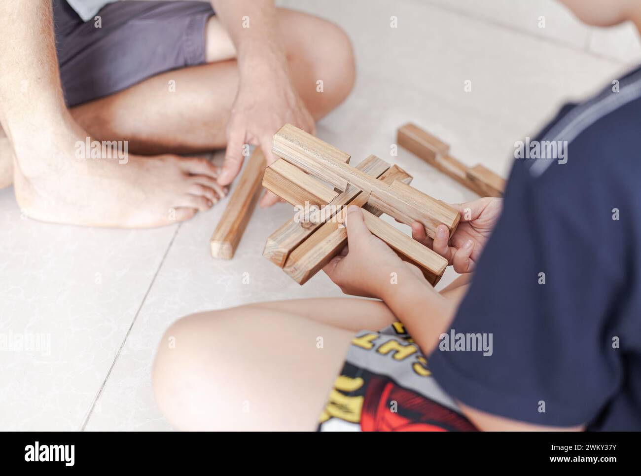 Les tweens et un adulte jouant des jouets de blocs de construction en bois ensemble dans un intérieur minimaliste léger Banque D'Images
