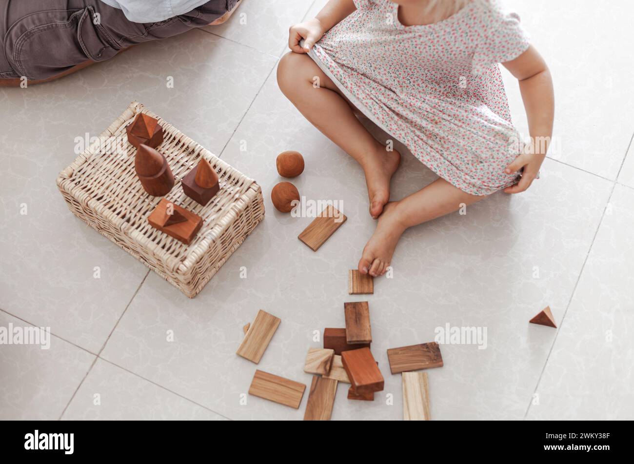 Un enfant jouant avec des jouets en bois et des blocs sur le sol Banque D'Images