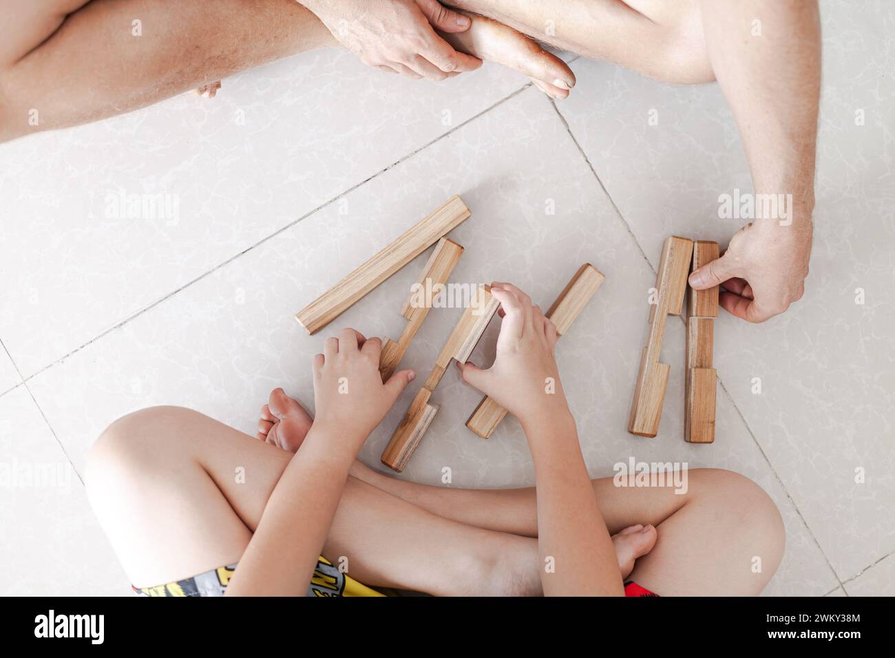 Les tweens et un adulte jouant des jouets de blocs de construction en bois ensemble dans un intérieur minimaliste léger Banque D'Images