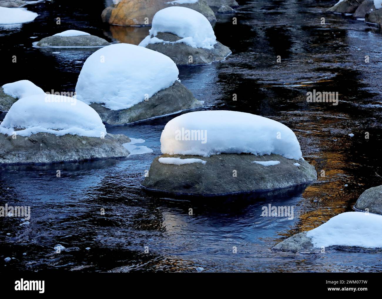Pierres couvertes de neige dans une rivière à la lumière du jour Banque D'Images