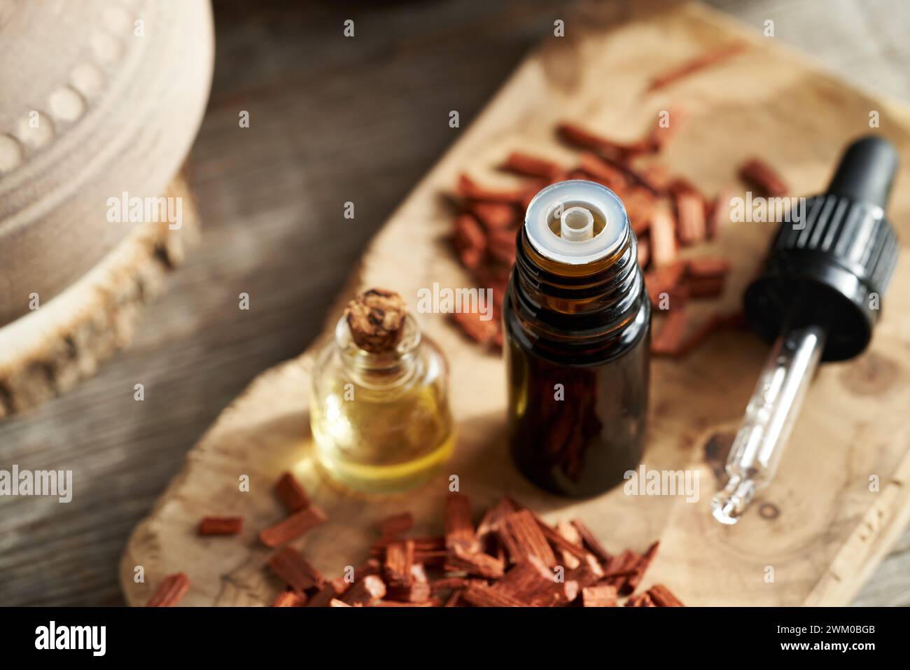 Une bouteille marron d'huile essentielle avec des copeaux de bois de santal rouge Banque D'Images