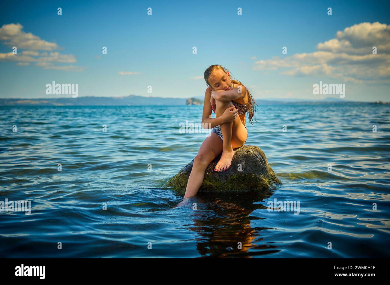 Fille se reposant sur le rocher dans le lac Bolsena, Italie Banque D'Images