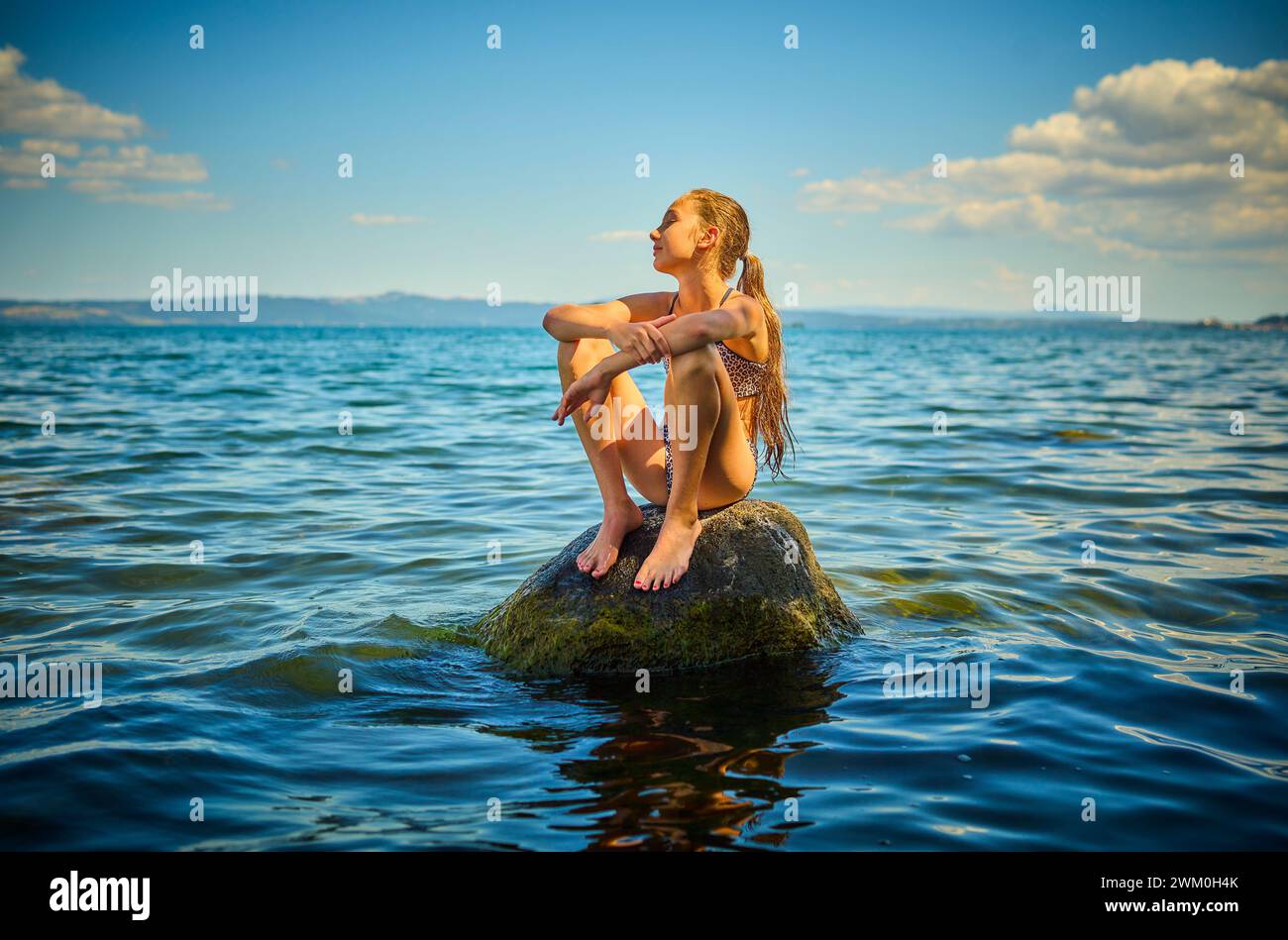 Fille assise sur le rocher dans le lac Bolsena, Italie Banque D'Images
