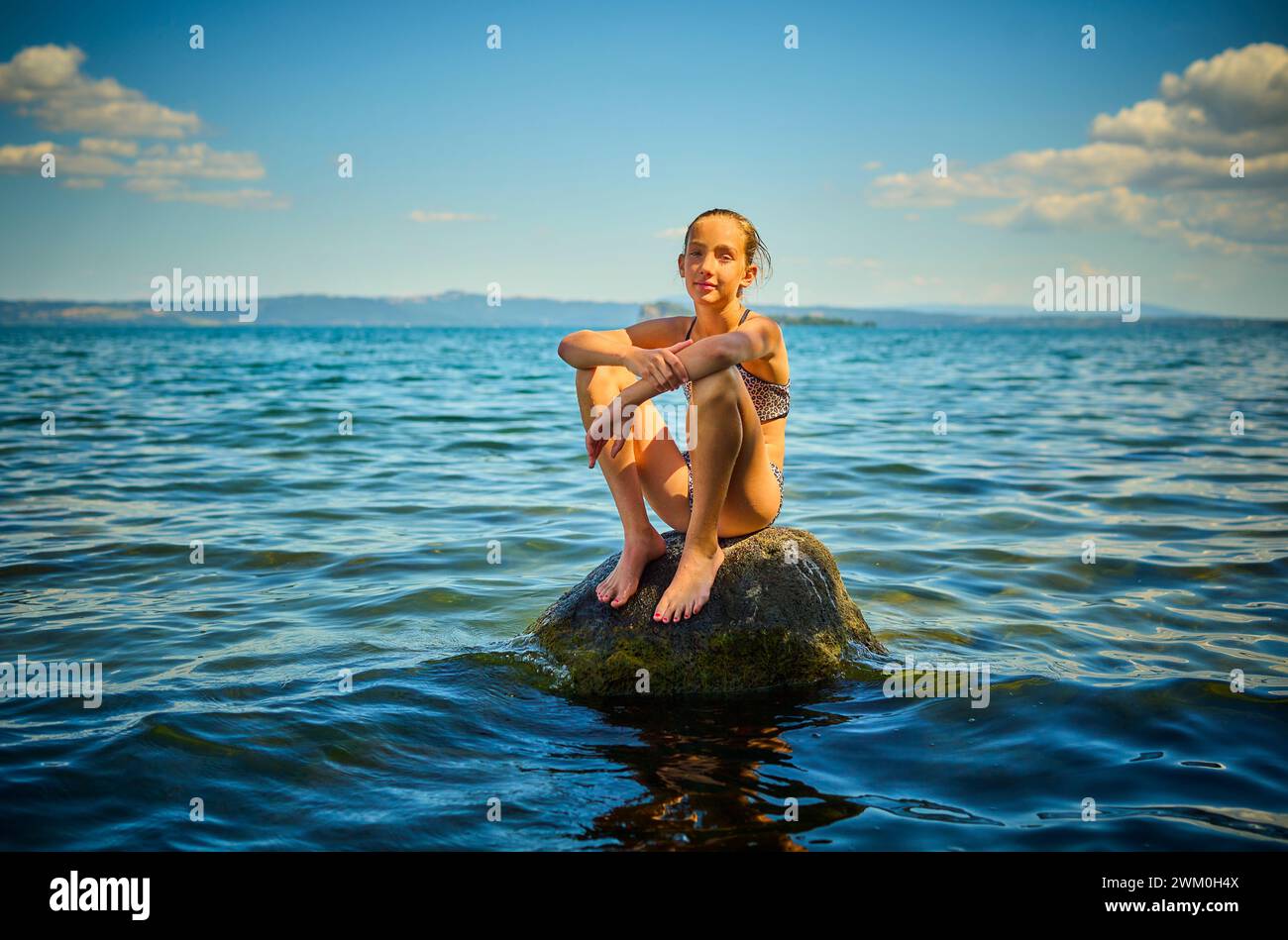 Fille assise sur le rocher dans le lac Bolsena, Italie Banque D'Images