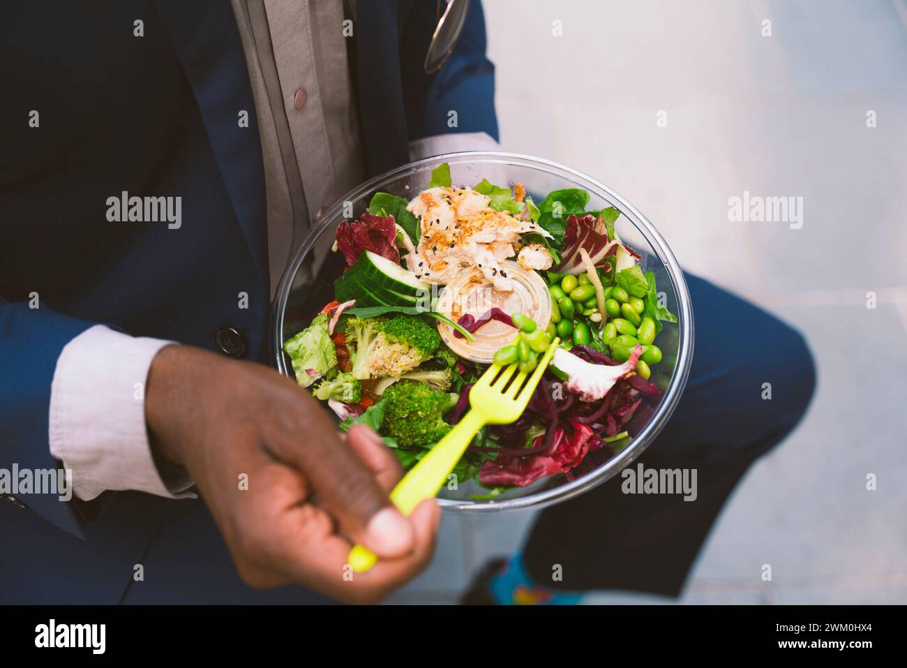 Homme d'affaires tenant une fourchette et ayant un bol de salade Banque D'Images