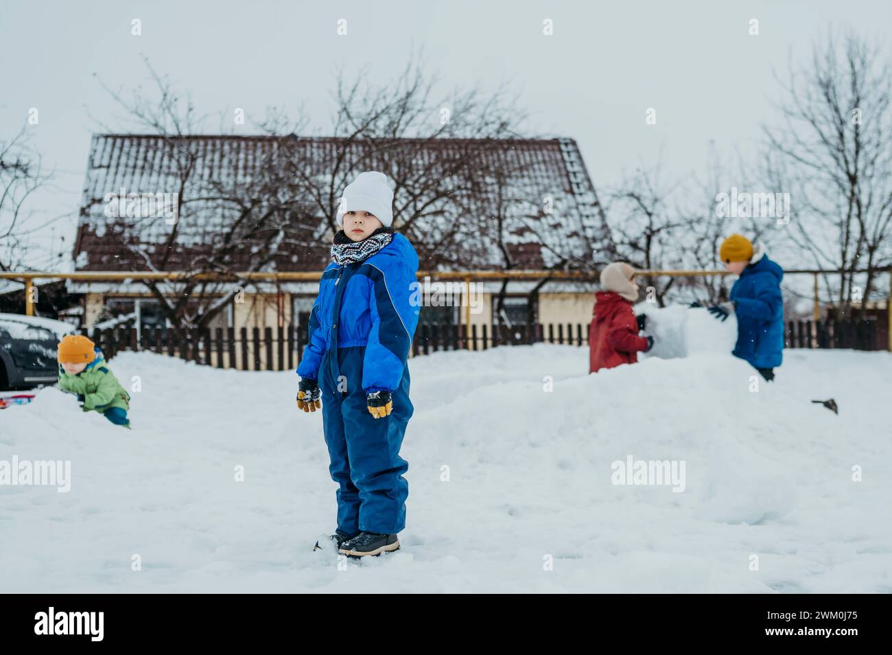 Enfants portant des vêtements chauds et jouant dans la neige Banque D'Images