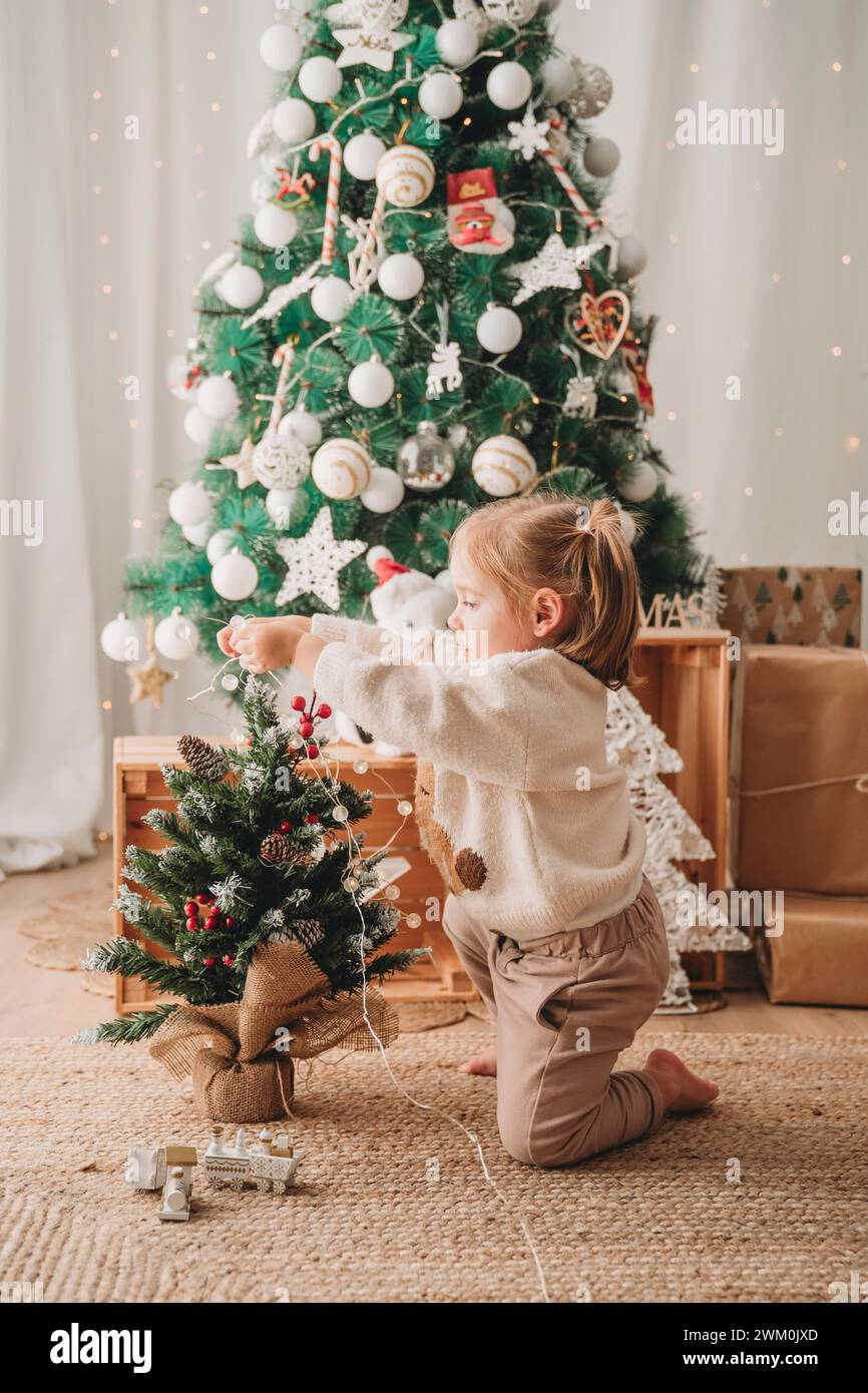 Fille décorant un petit arbre de Noël à la maison Banque D'Images