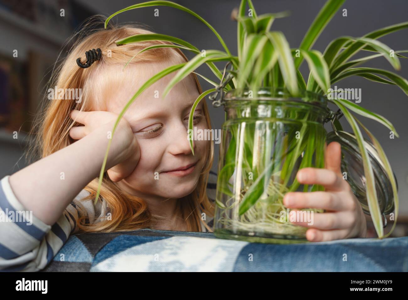 Fille souriante avec une plante d'araignée à la maison Banque D'Images