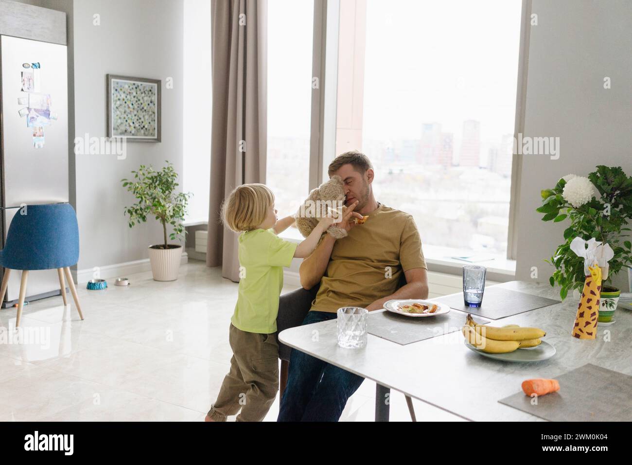 Garçon jouant avec son père près de la table à manger à la maison Banque D'Images