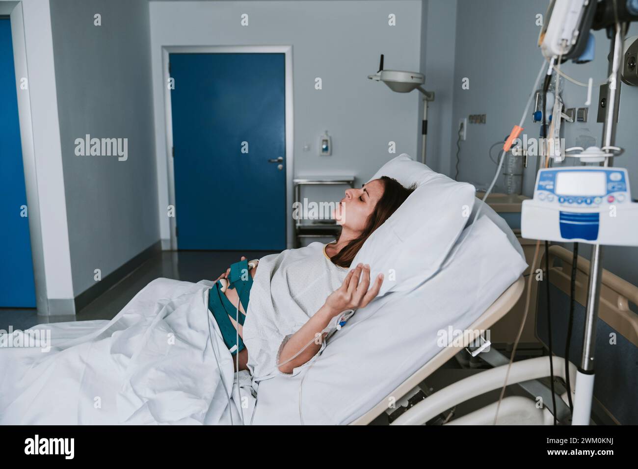 Femme enceinte dans la douleur couchée sur le lit à l'intérieur de la salle d'accouchement Banque D'Images