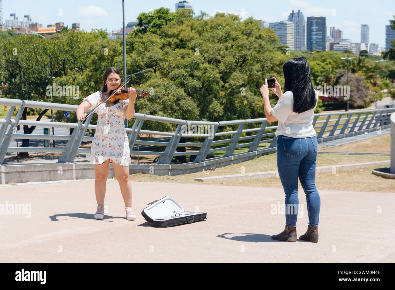 Femme touriste debout à l'extérieur prenant des photos avec son téléphone de violoniste vénézuélien Latina busker à Buenos Aires travaillant à faire de la musique, de la musique et du peop Banque D'Images