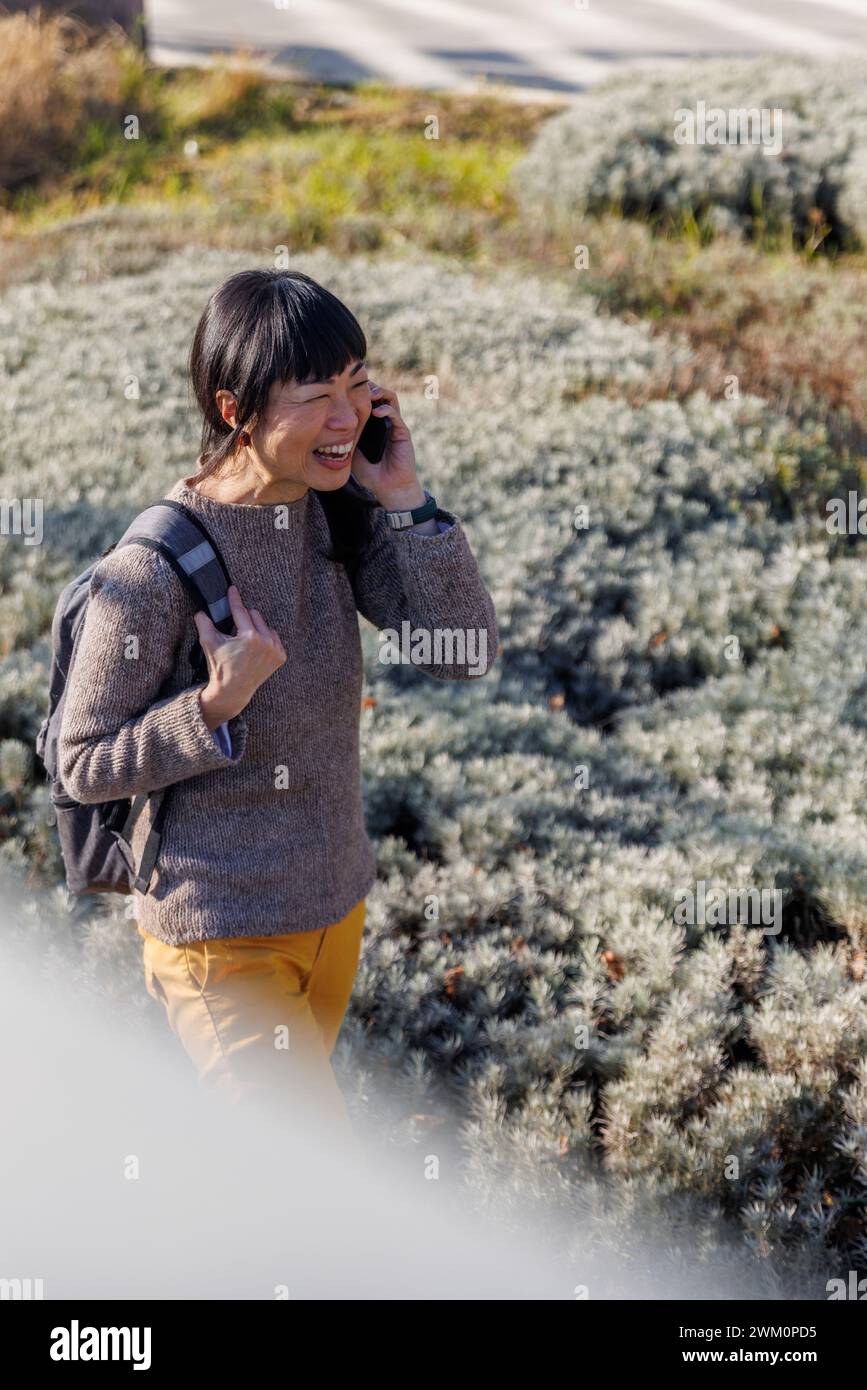 Femme heureuse parlant au téléphone portable près des plantes Banque D'Images