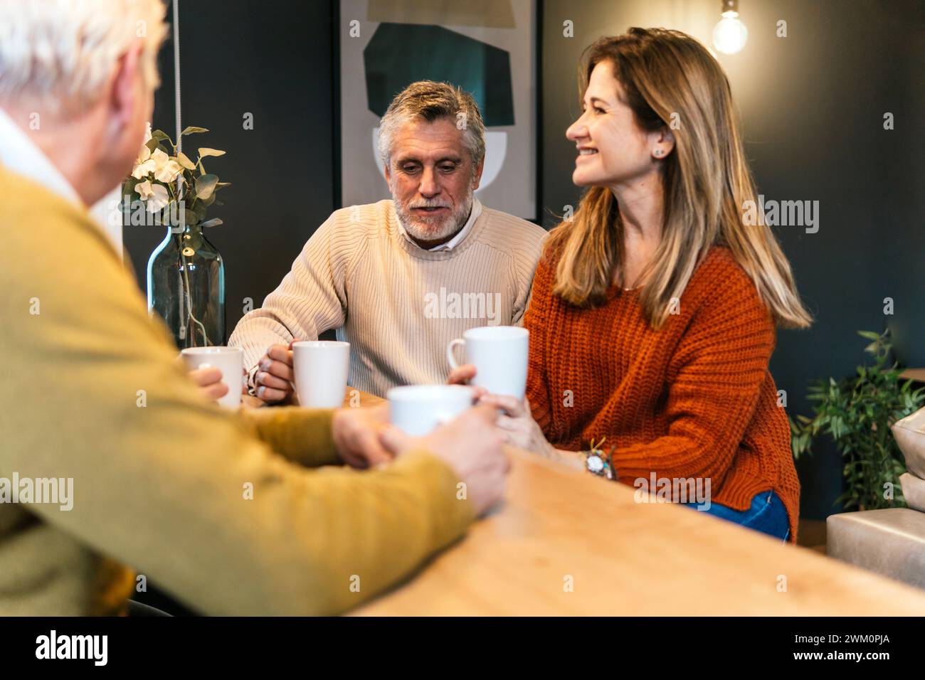 Heureux amis avec tasse de café discutant à table Banque D'Images
