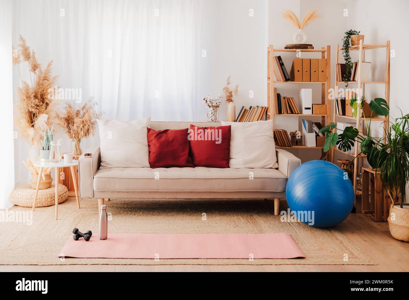 Tapis d'exercice sur la moquette près du canapé et ballon de fitness dans la salle de séjour Banque D'Images
