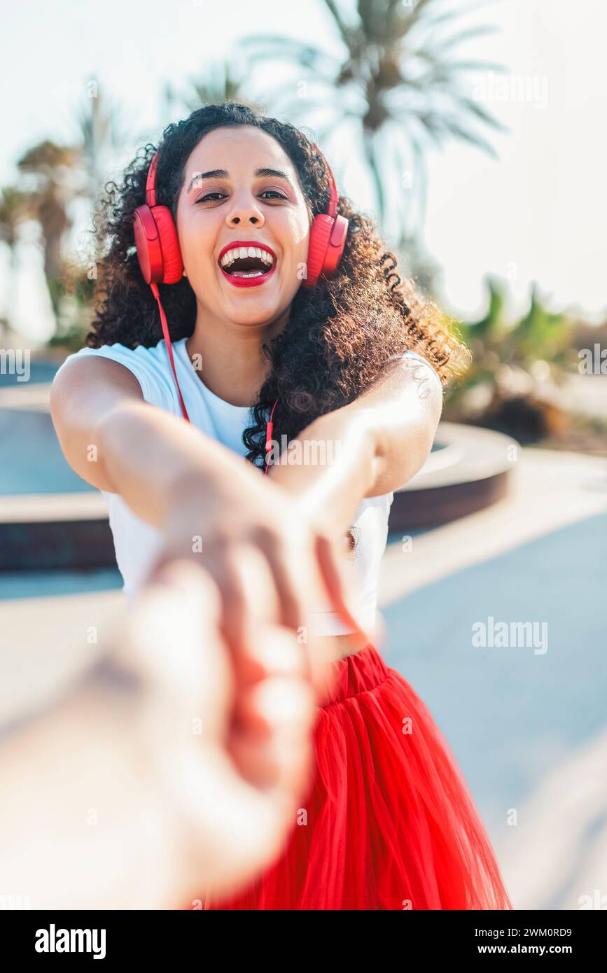Femme heureuse écoutant de la musique et tenant la main d'un ami au skate Park Banque D'Images
