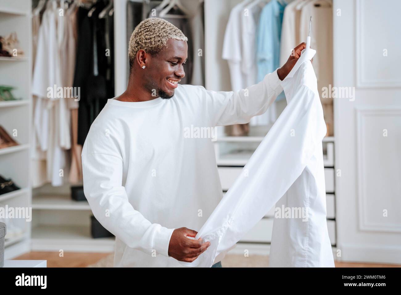 Homme heureux regardant le t-shirt devant le placard Banque D'Images