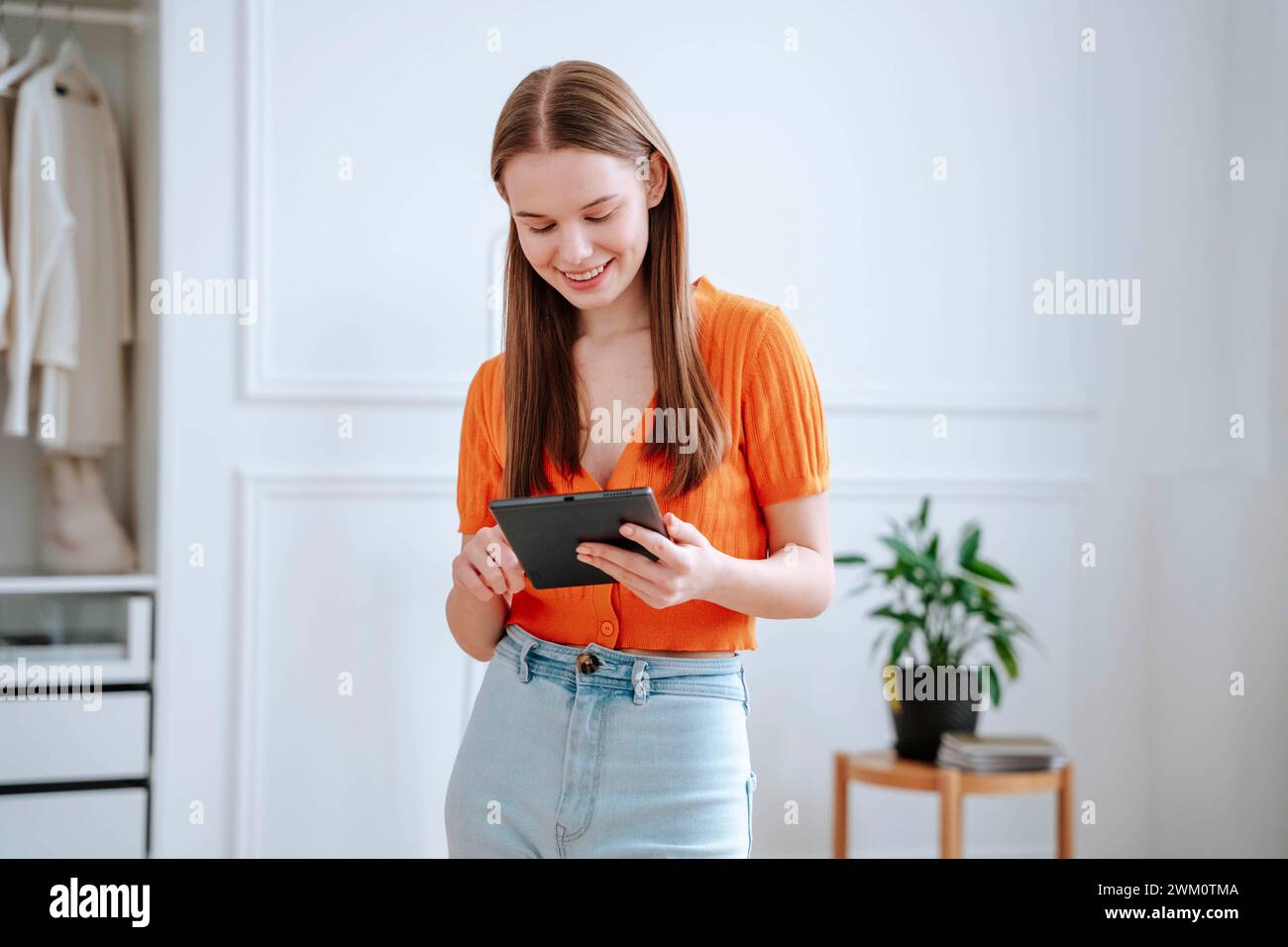 Bonne jeune femme utilisant un PC tablette à la maison Banque D'Images