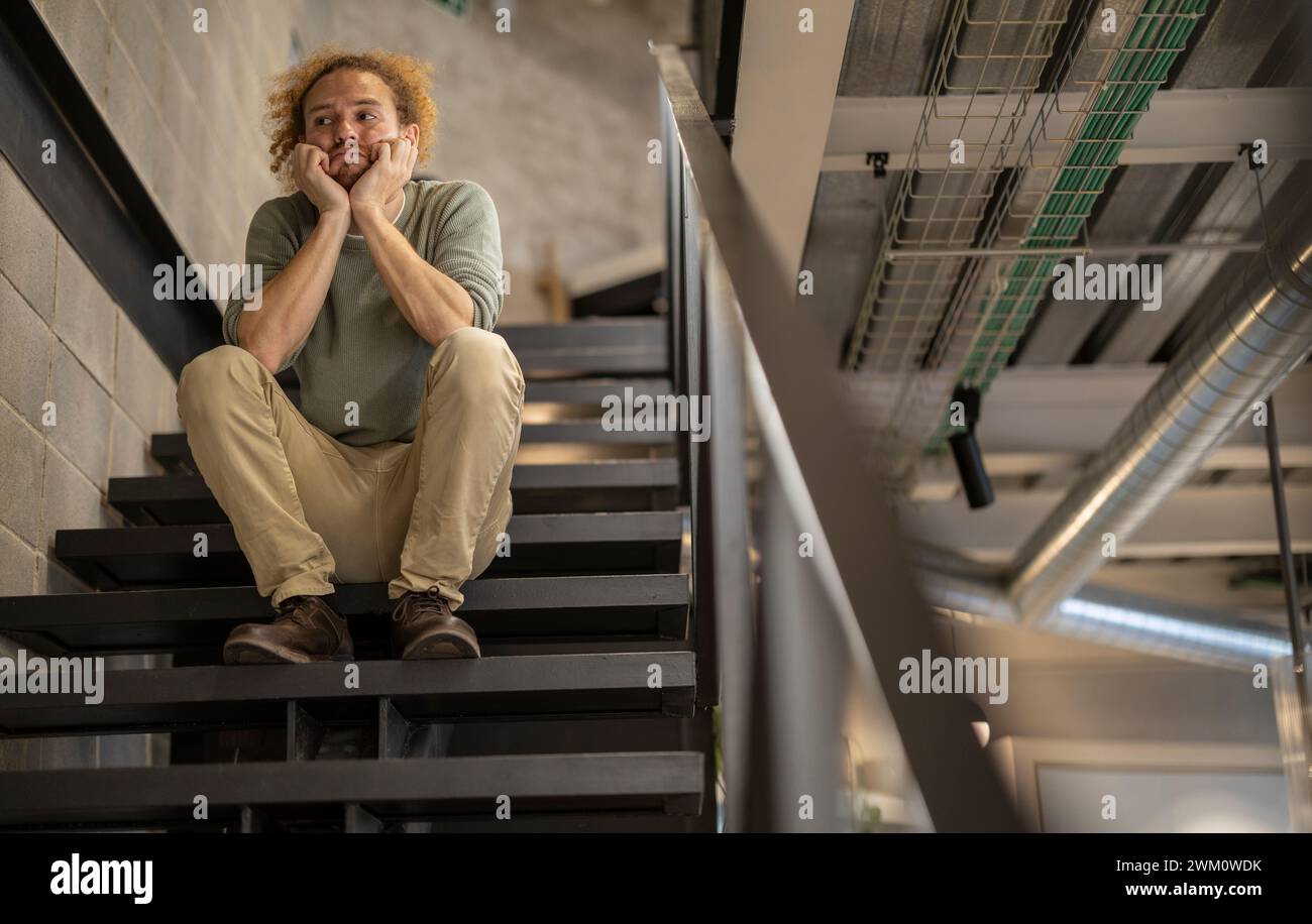 Homme d'affaires bouleversé assis sur l'escalier au bureau Banque D'Images