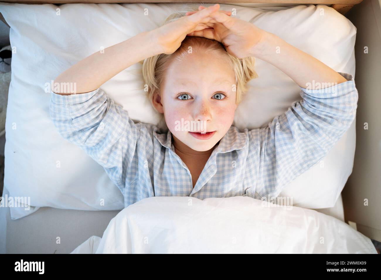 Garçon avec la tête dans les mains couché sur le lit à la maison Banque D'Images