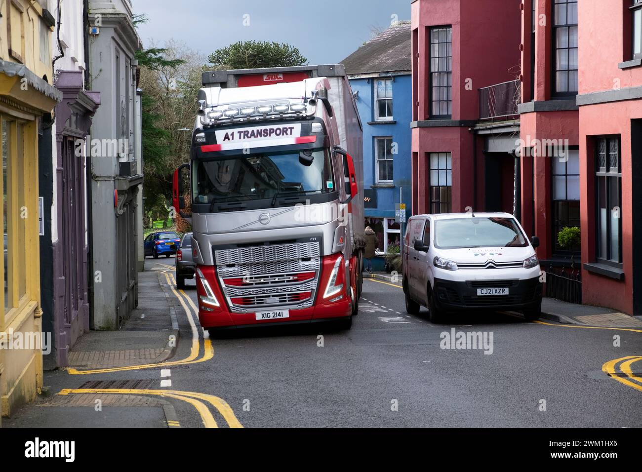 Camion poids lourd conduisant sur Rhosmaen Street devant les voitures garées devant les magasins la route étroite principale à travers une petite rue dans la ville de Llandeilo Wales UK 2024 Banque D'Images