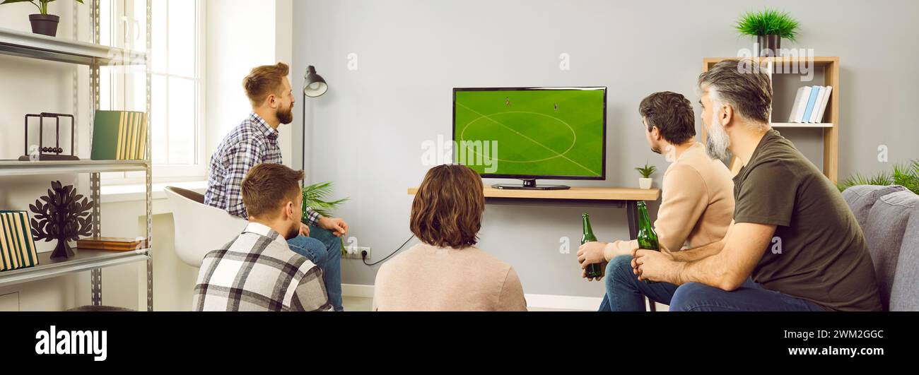 Groupe d'amis barbus matures regardant un match de football à la télévision à la maison avec de la bière. Banque D'Images
