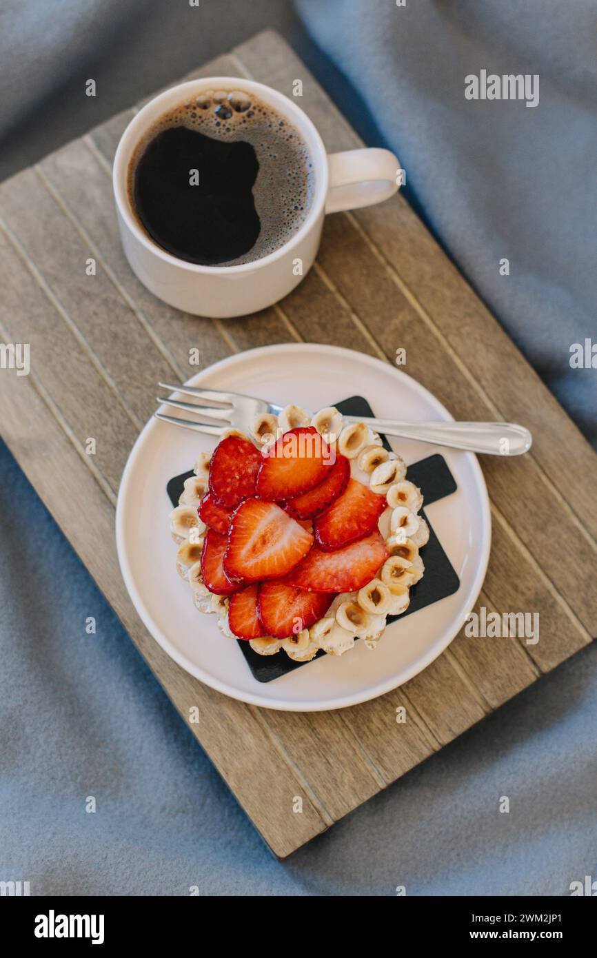 Tasse de café noir et un gâteau aux fraises sur un fond gris. Pose à plat. Banque D'Images