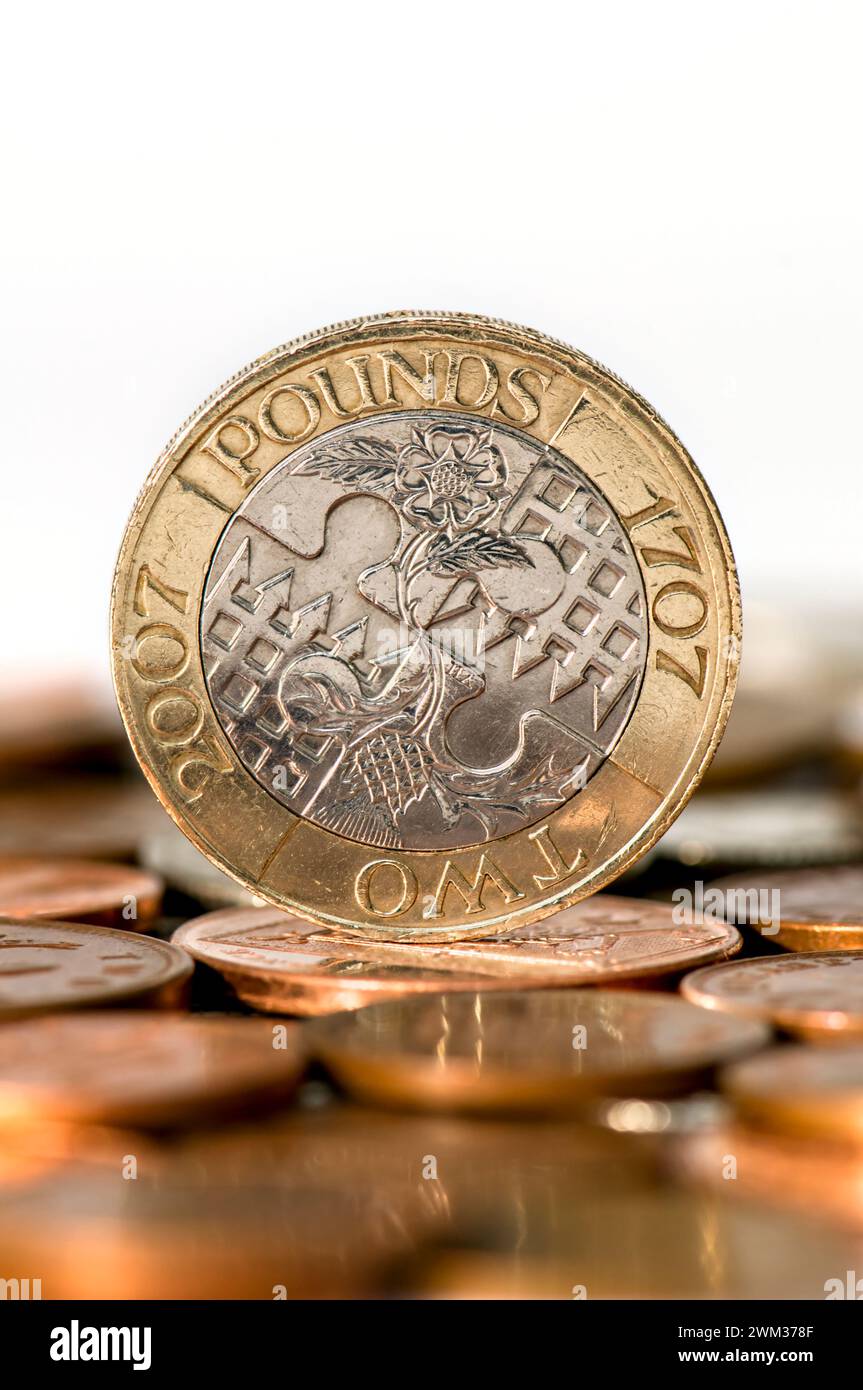Plan studio d'une pièce de deux livres sterling debout sur une table avec des pièces hors foyer au premier plan sur un fond blanc Banque D'Images
