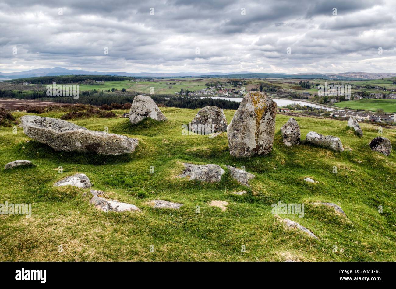 Petites pierres debout à Ord Hill, avec le village de Lairg derrière elle, Lairg, Écosse, Royaume-Uni pris par un jour nuageux et couvert Banque D'Images