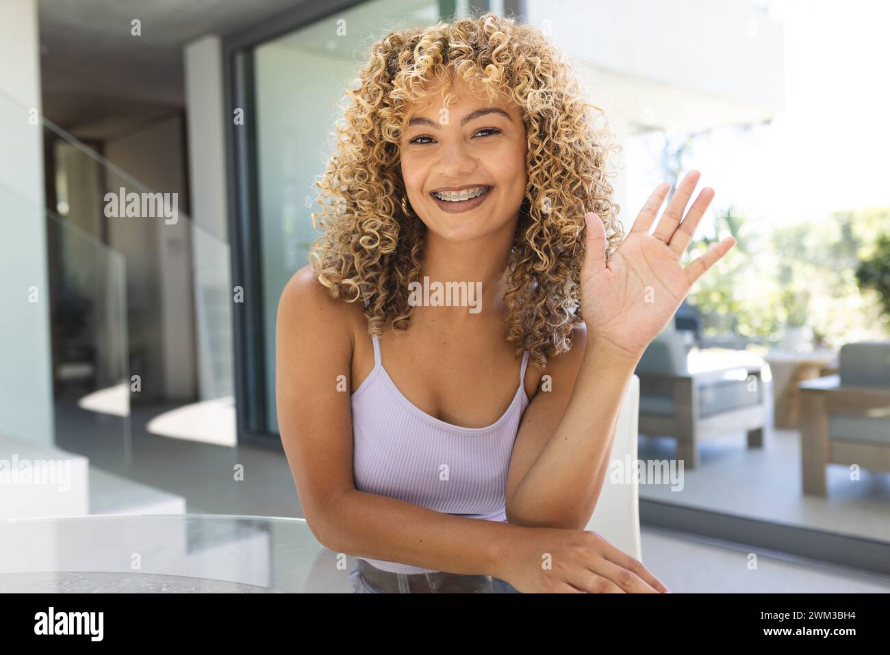 Jeune femme biraciale sourit chaleureusement à la maison lors d'un appel vidéo Banque D'Images