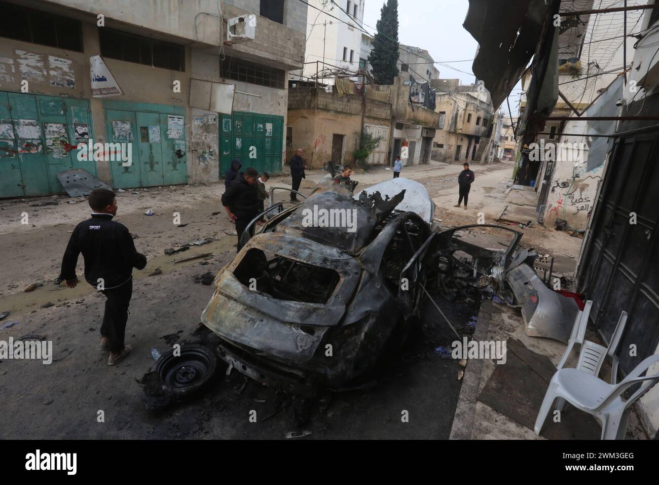 Jenin. 23 février 2024. Les gens se rassemblent autour d’une voiture détruite lors d’une frappe aérienne israélienne dans la ville de Djénine, en Cisjordanie, le 23 février 2024. Le nombre de morts palestiniennes dans la ville de Djénine en Cisjordanie suite à une frappe aérienne israélienne sur un véhicule est passé à deux vendredi, après qu'un garçon de 17 ans a succombé blessé, selon l'agence de presse officielle palestinienne Wafa. Crédit : Nidal Eshtayeh/Xinhua/Alamy Live News Banque D'Images