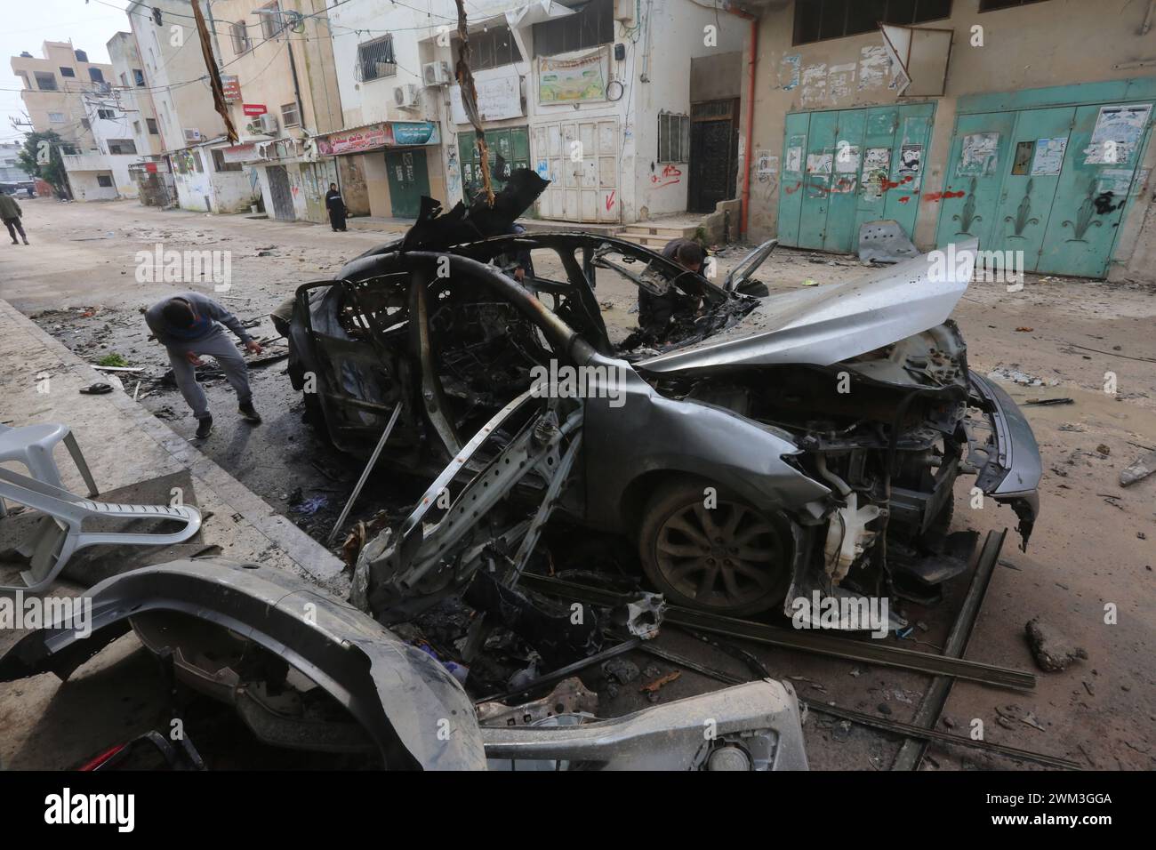 Jenin. 23 février 2024. Les gens inspectent une voiture détruite lors d’une frappe aérienne israélienne dans la ville de Djénine en Cisjordanie, le 23 février 2024. Le nombre de morts palestiniennes dans la ville de Djénine en Cisjordanie suite à une frappe aérienne israélienne sur un véhicule est passé à deux vendredi, après qu'un garçon de 17 ans a succombé blessé, selon l'agence de presse officielle palestinienne Wafa. Crédit : Nidal Eshtayeh/Xinhua/Alamy Live News Banque D'Images