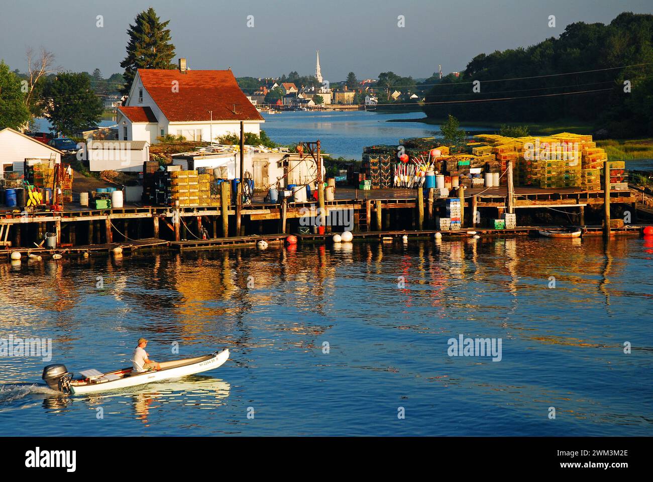 Un petit bateau avec un moteur hors-bord passe devant le quai de pêche rempli de casiers à homard à Portsmouth, New Hampshire, sur la côte de la Nouvelle-Angleterre Banque D'Images