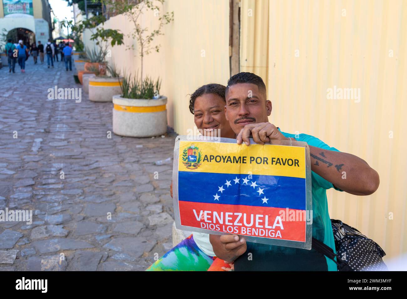 Oaxaca, Mexique - Un homme et une femme qui tentent de se rendre du Venezuela aux États-Unis tiennent une pancarte demandant de l'aide. Banque D'Images