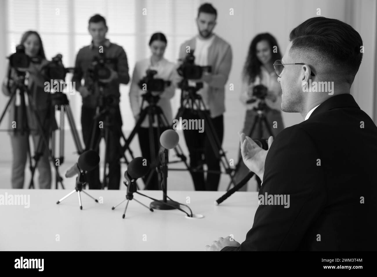 Homme d'affaires donnant une interview aux journalistes à l'intérieur. Effet noir et blanc Banque D'Images