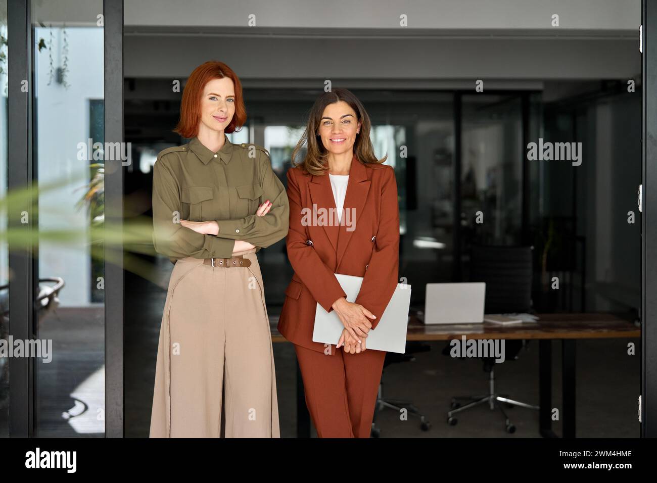 Portrait de deux femmes d'affaires élégantes heureuses debout au travail dans un bureau moderne. Banque D'Images