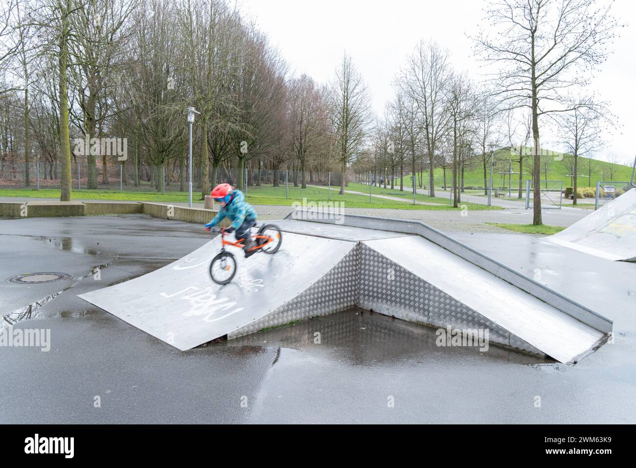 Un petit garçon accélère sur la piste avec son vélo. Photo d'un cycliste avec flou de mouvement. Développement et activités de l'enfant. Cyclisme et sports. Banque D'Images