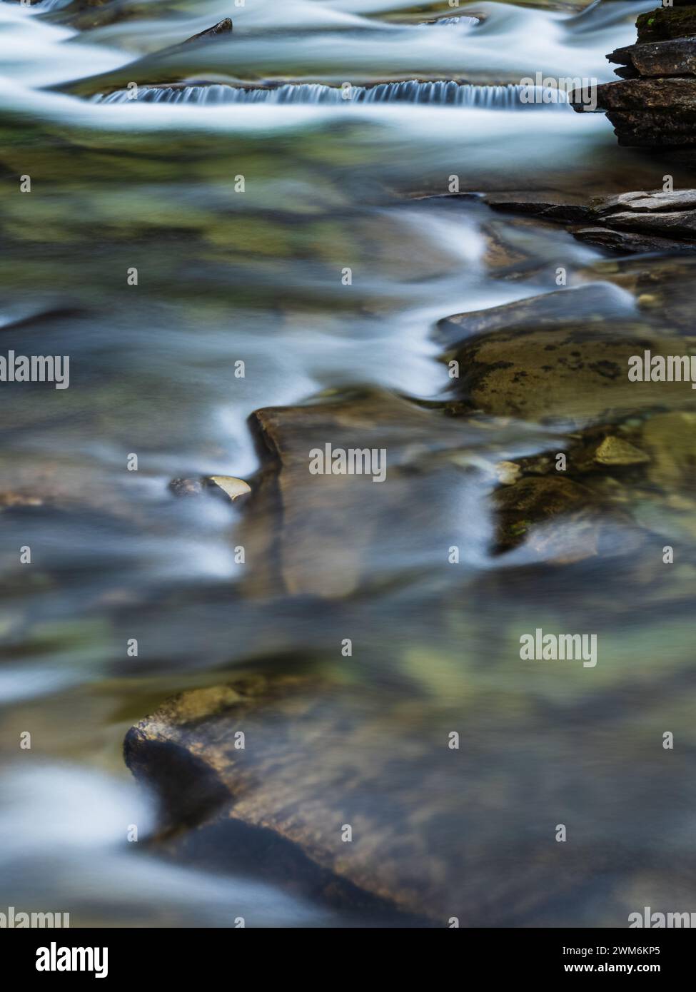 La paisible rivière Ljusnan serpente à travers le paysage accidenté de Härjedalen, son eau cascadant sur des rochers et des galets. La lumière tamisée et douce Banque D'Images