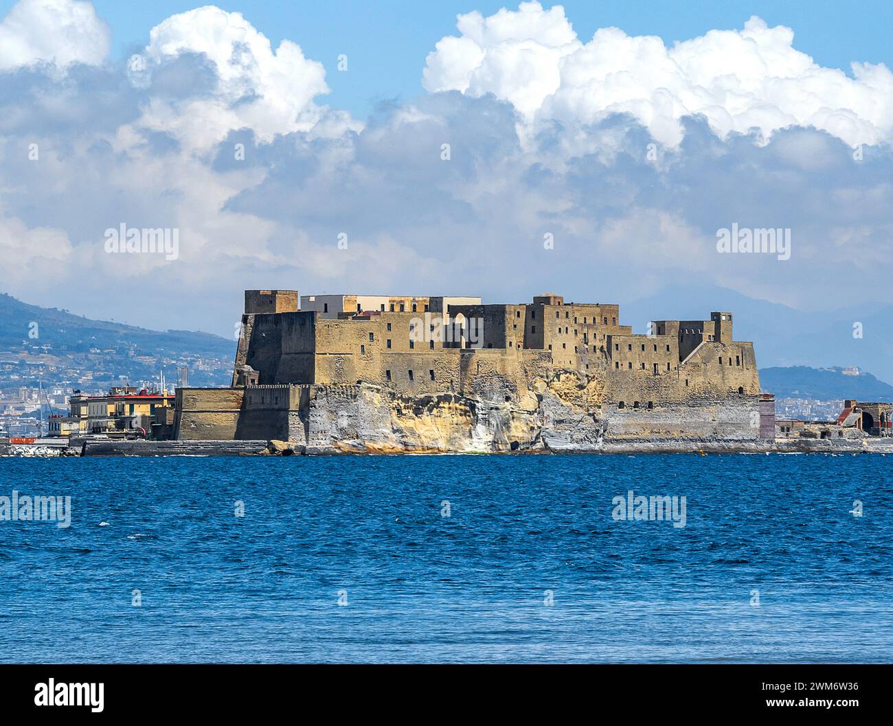 Au premier plan la jetée de la baie de Naples et la mer bleue avec un voilier, en arrière-plan l'ancien Castel Dell'Ovo sur une journée ensoleillée Banque D'Images