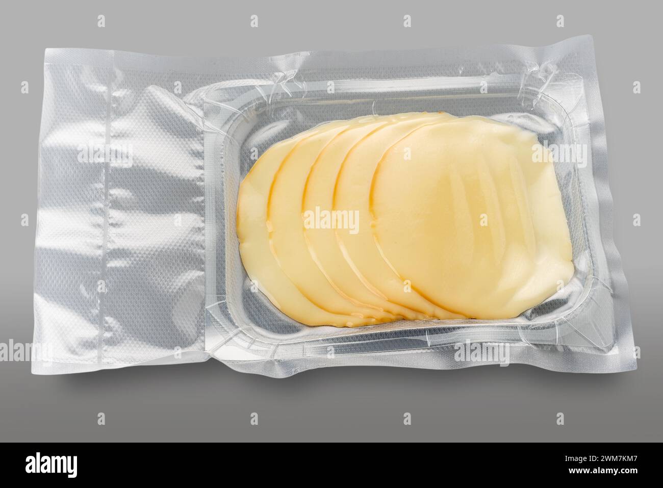 Fromage provolone tranché dans un plateau en plastique emballé sous vide isolé sur gris avec chemin de découpage inclus Banque D'Images