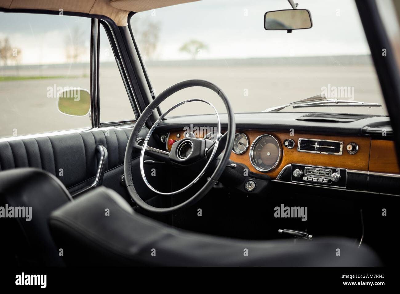 Intérieur de voiture classique avec cuir noir et garniture de porte. Intérieur de la vieille voiture des années 1960 avec panneau avant en bois. Banque D'Images