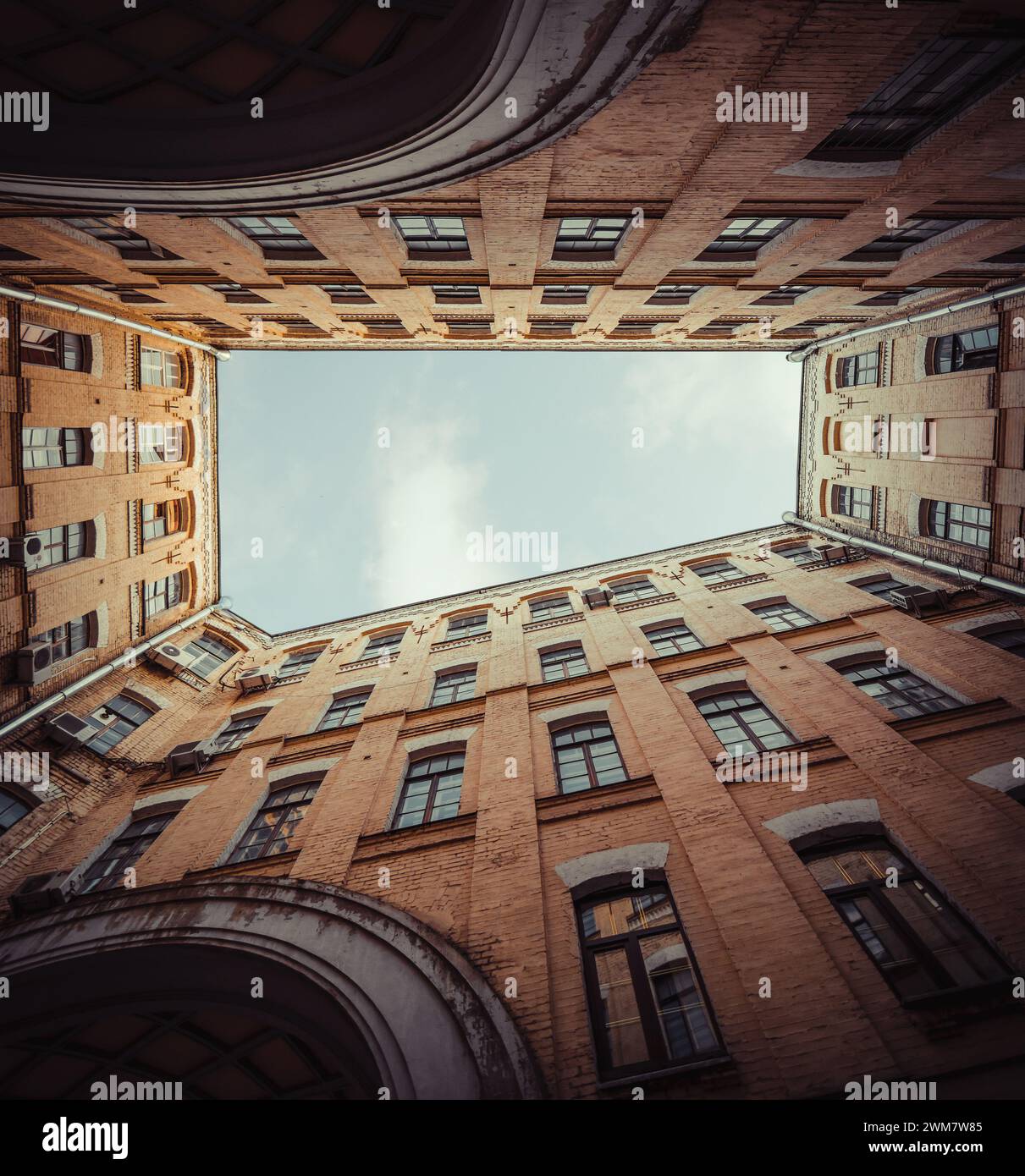 Cour du 19ème siècle - regardant le ciel. Lumière bien à l'intérieur d'un bâtiment en brique dans la vieille ville. Façade avec beaucoup de fenêtres. Banque D'Images