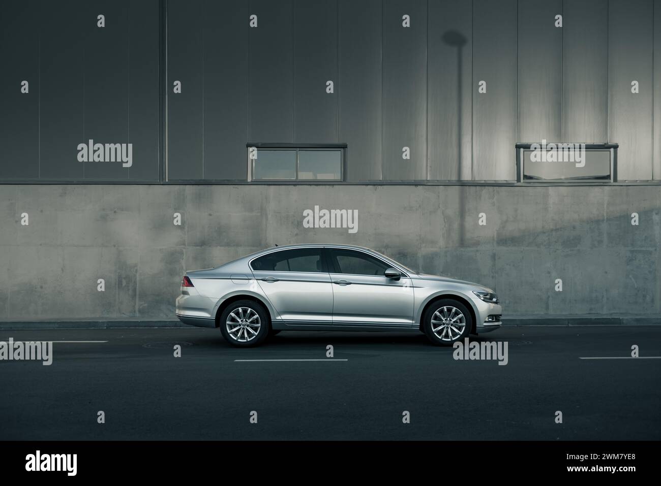 Berline Volkswagen Passat argentée garée devant le mur gris - vue latérale Banque D'Images