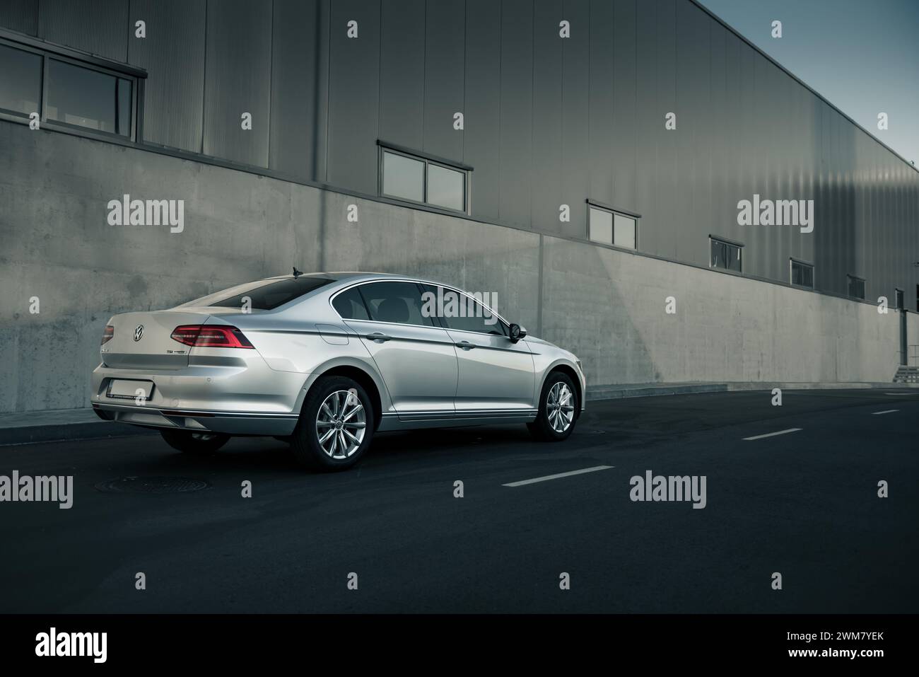 Silver Volkswagen Passat garé près de l'entrepôt. Perspective vue de trois quarts arrière de la berline allemande près du mur de béton gris. Banque D'Images