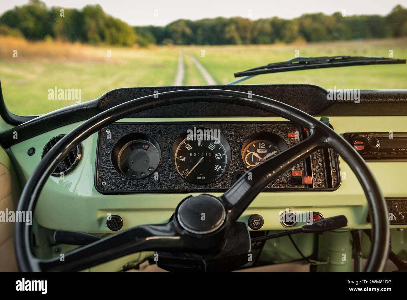 Intérieur du Volkswagen transporter T2 Classic bus : volant et tableau de bord. Campagne route non pavée en arrière-plan. Banque D'Images